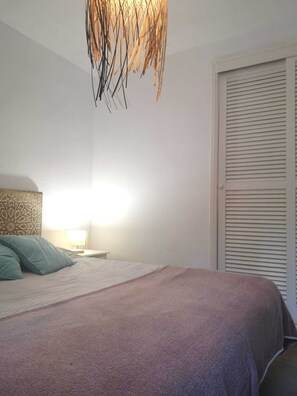 A bedroom with a bed, a nightstand, a lamp, and a closet. - Golf & Beach Holiday Home, Menorca (Son Parc)