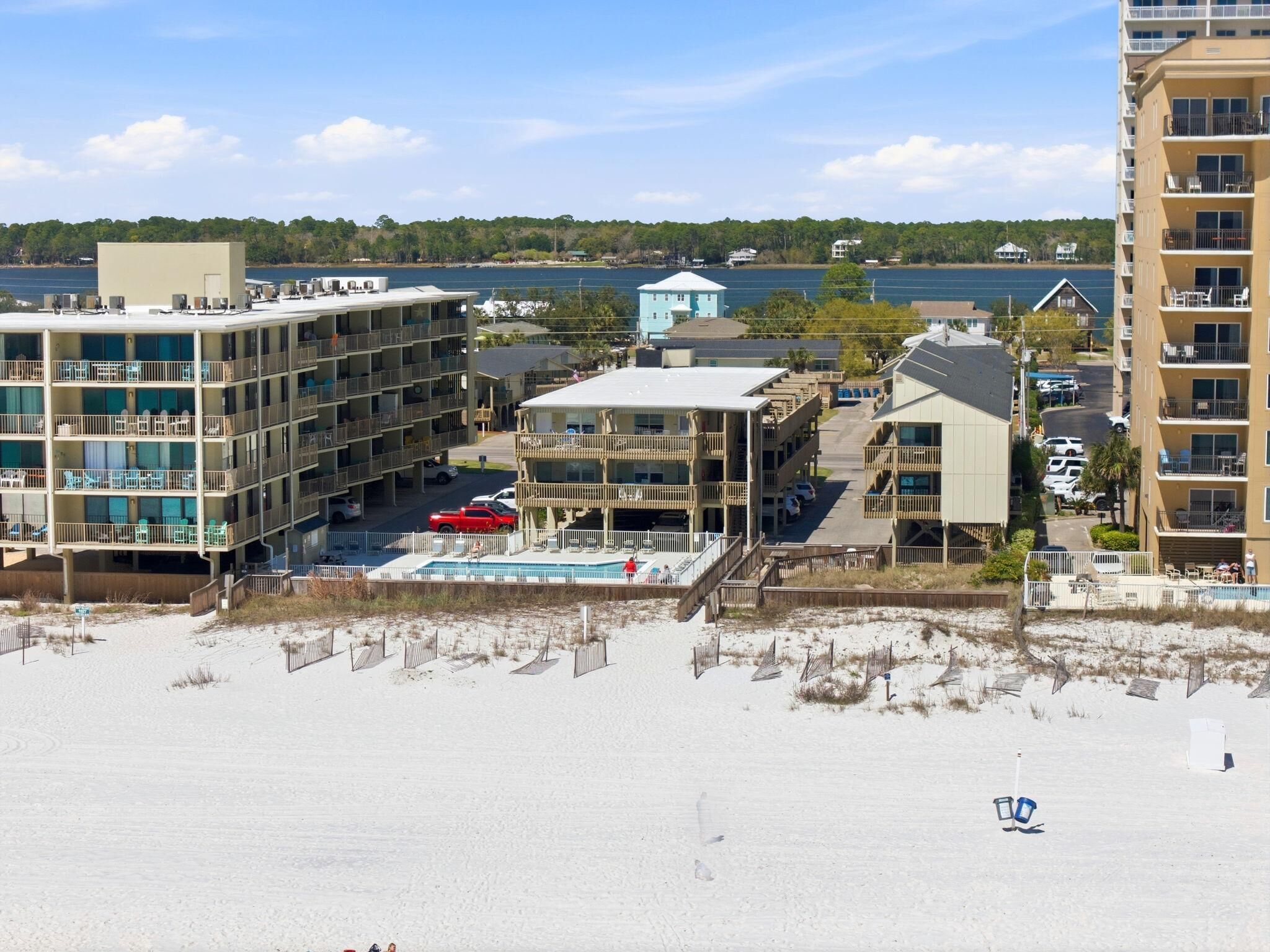 Un hotel frente a la playa con varias edificaciones, una piscina y vistas al océano.
