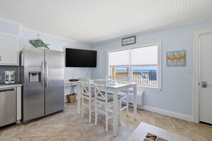 A kitchen with a refrigerator, a coffee maker, and a dining table with chairs. - Gulf Village 207 (Gulf Shores)