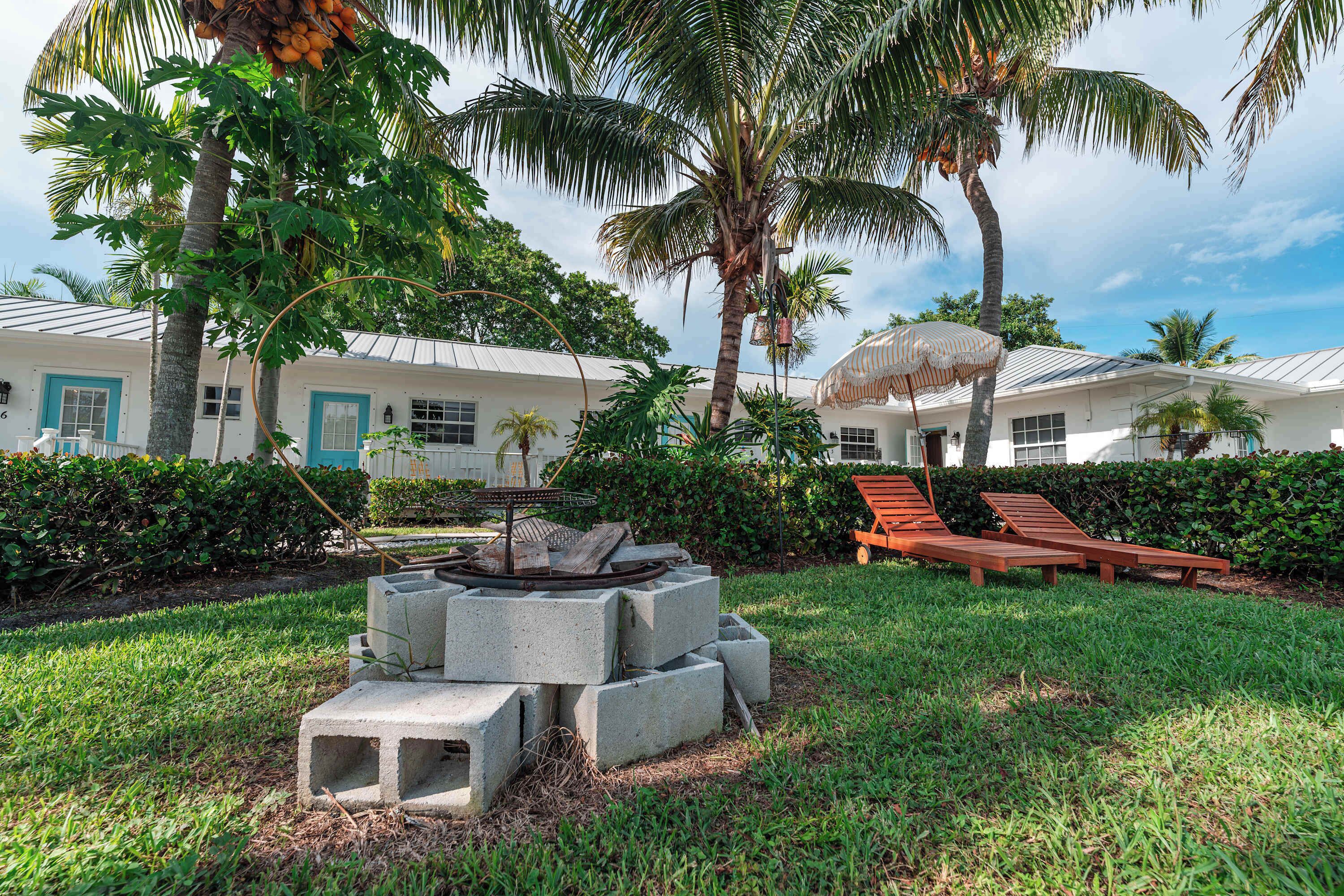 A resort with a pool area, lounge chairs, and a fire pit surrounded by greenery.