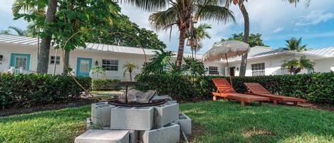 A resort with a pool area, lounge chairs, and a fire pit surrounded by greenery.