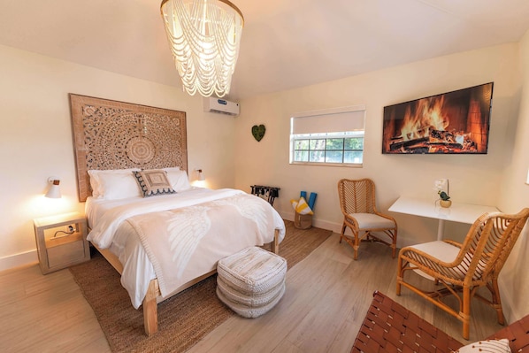 A bedroom with a bed, bedside table, wall-mounted TV, and a window.