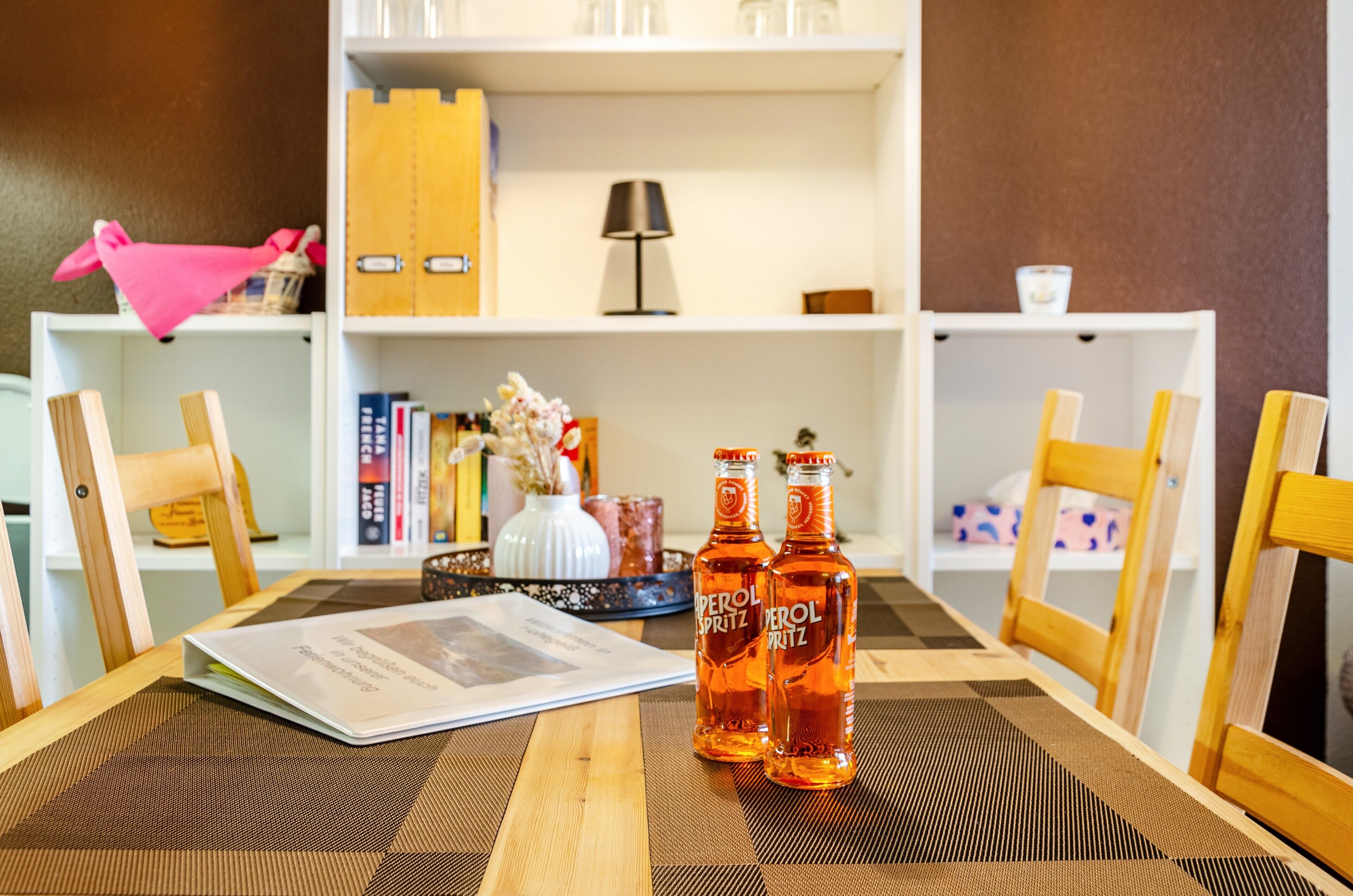 A dining table with two bottles of beer, a menu, and a decorative vase.