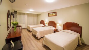 A hotel room with three beds, a desk, a mirror, and a picture on the wall. - Britania San Borja (Lima)