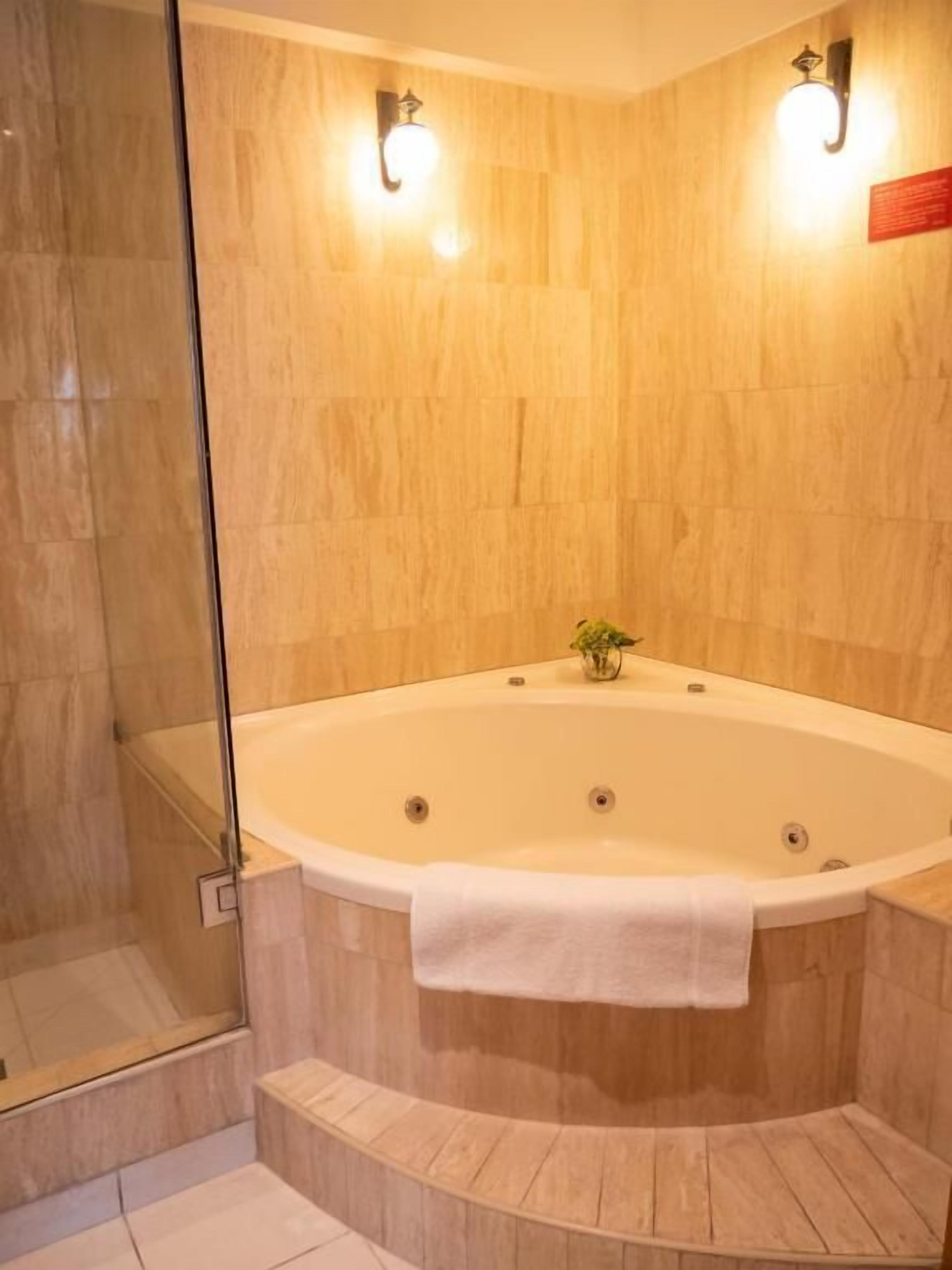 A bathroom with a freestanding bathtub, a glass shower enclosure, and wooden wall panels.