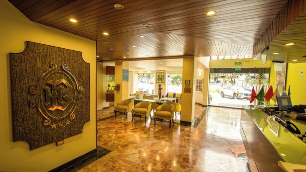 A lobby with a reception desk, seating area, and a wall-mounted decorative piece. - Britania San Borja (Lima)