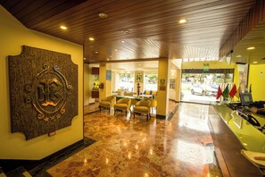 A lobby with a reception desk, seating area, and a wall-mounted decorative piece.