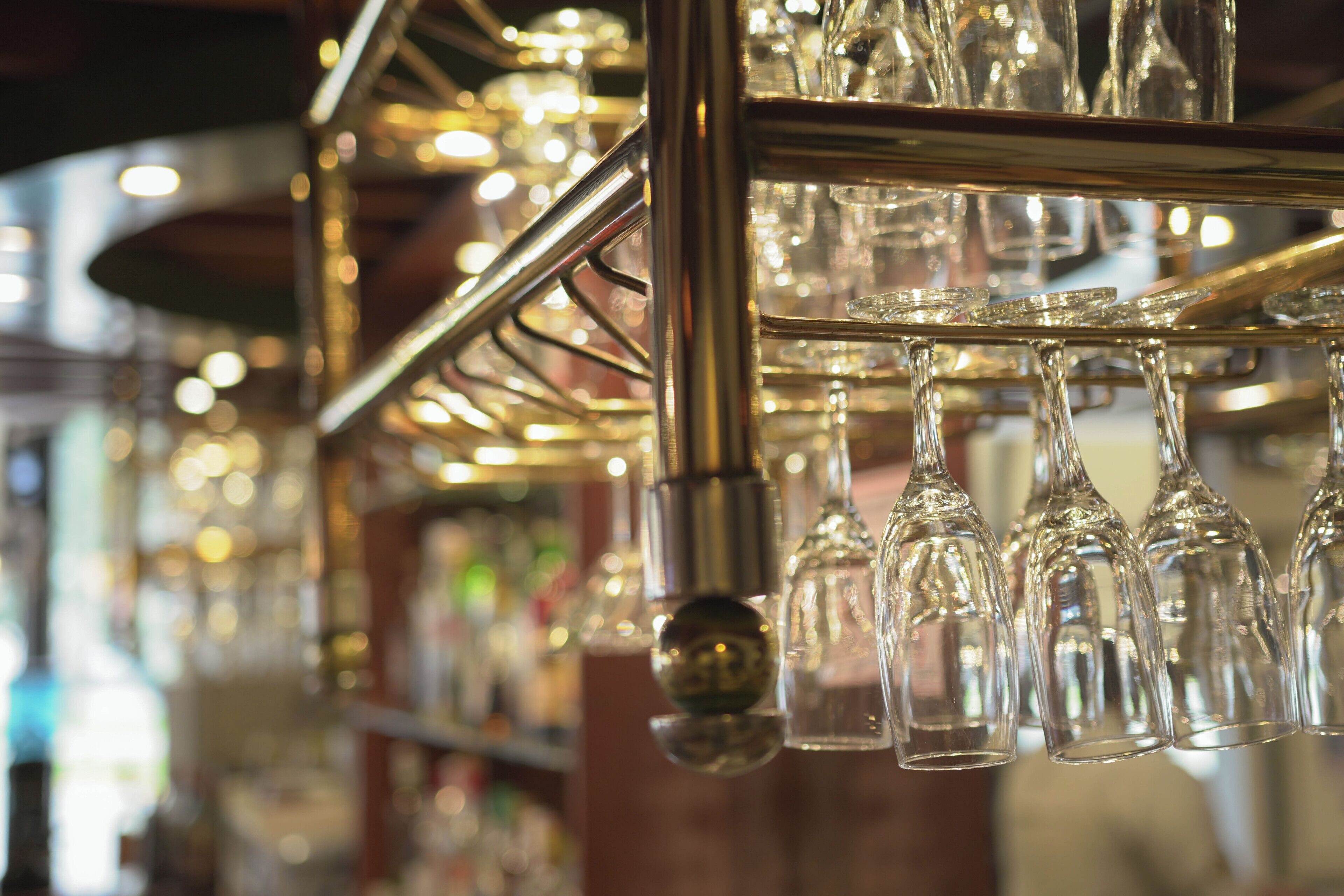 A bar area with multiple hanging wine glasses and a metal rack.