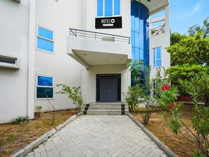 Une entrée d’hôtel moderne, avec un panneau indicateur, des marches et une allée pavée.