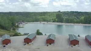 A lakeside view with four cabins and a sandy beach. - Beautiful 1-bedroom Cabin #5 with AC overlooking swim pond (Rayville)