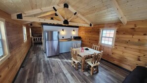 A wooden cabin interior with a dining area, kitchen, and a loft space. - Beautiful 1-bedroom Cabin #5 with AC overlooking swim pond (Rayville)