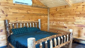 A wooden cabin interior with a bed, wooden walls, and a ceiling fan. - Beautiful 1-bedroom Cabin #5 with AC overlooking swim pond (Rayville)