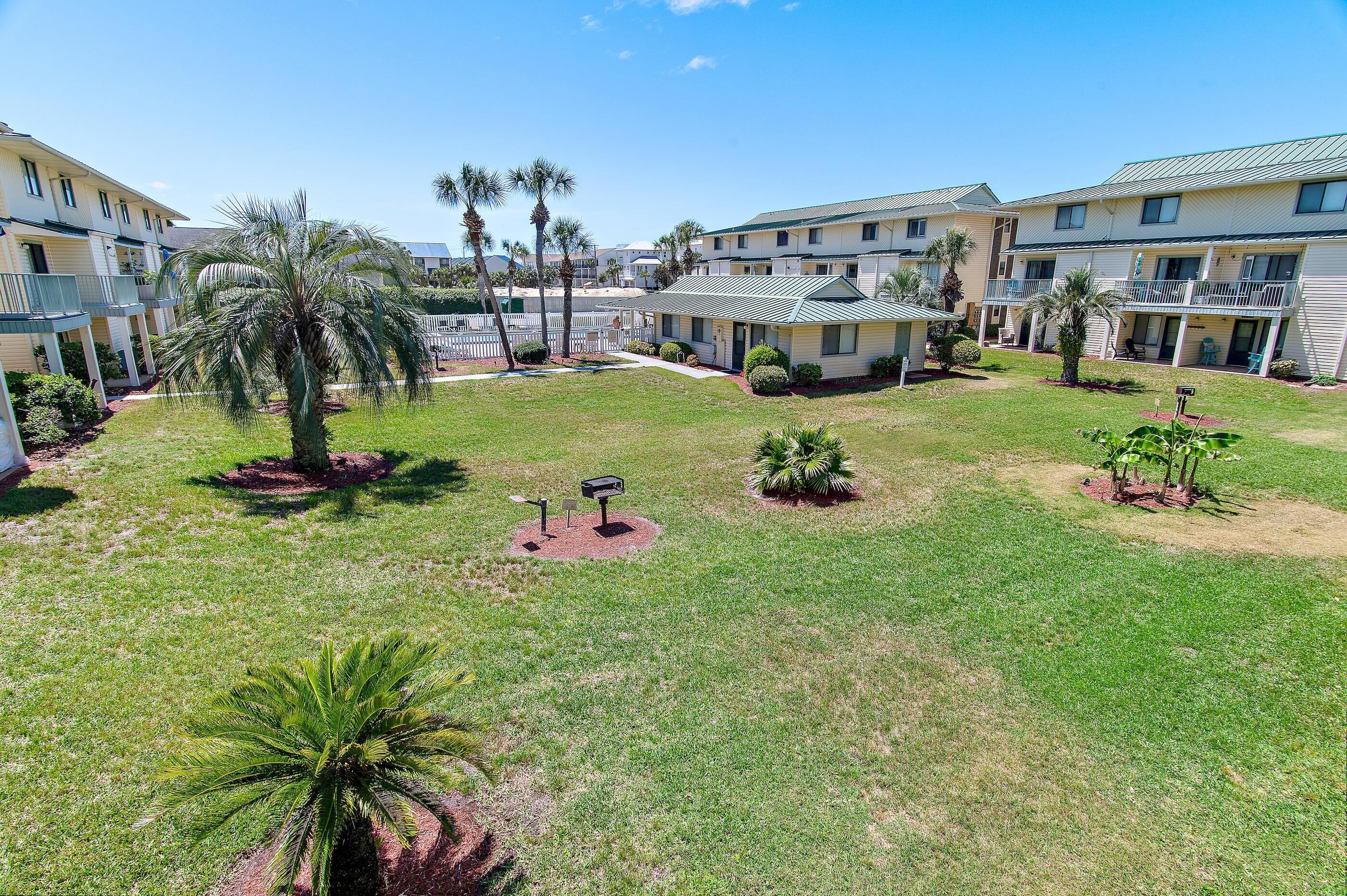 A hotel courtyard with multiple buildings, palm trees, and a well-maintained lawn.