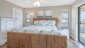 A bedroom with a bed, a ceiling fan, a nightstand, and a window with blinds.