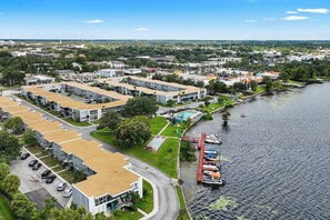 An aerial view of a residential area with modern buildings, a marina, and a large body of water.