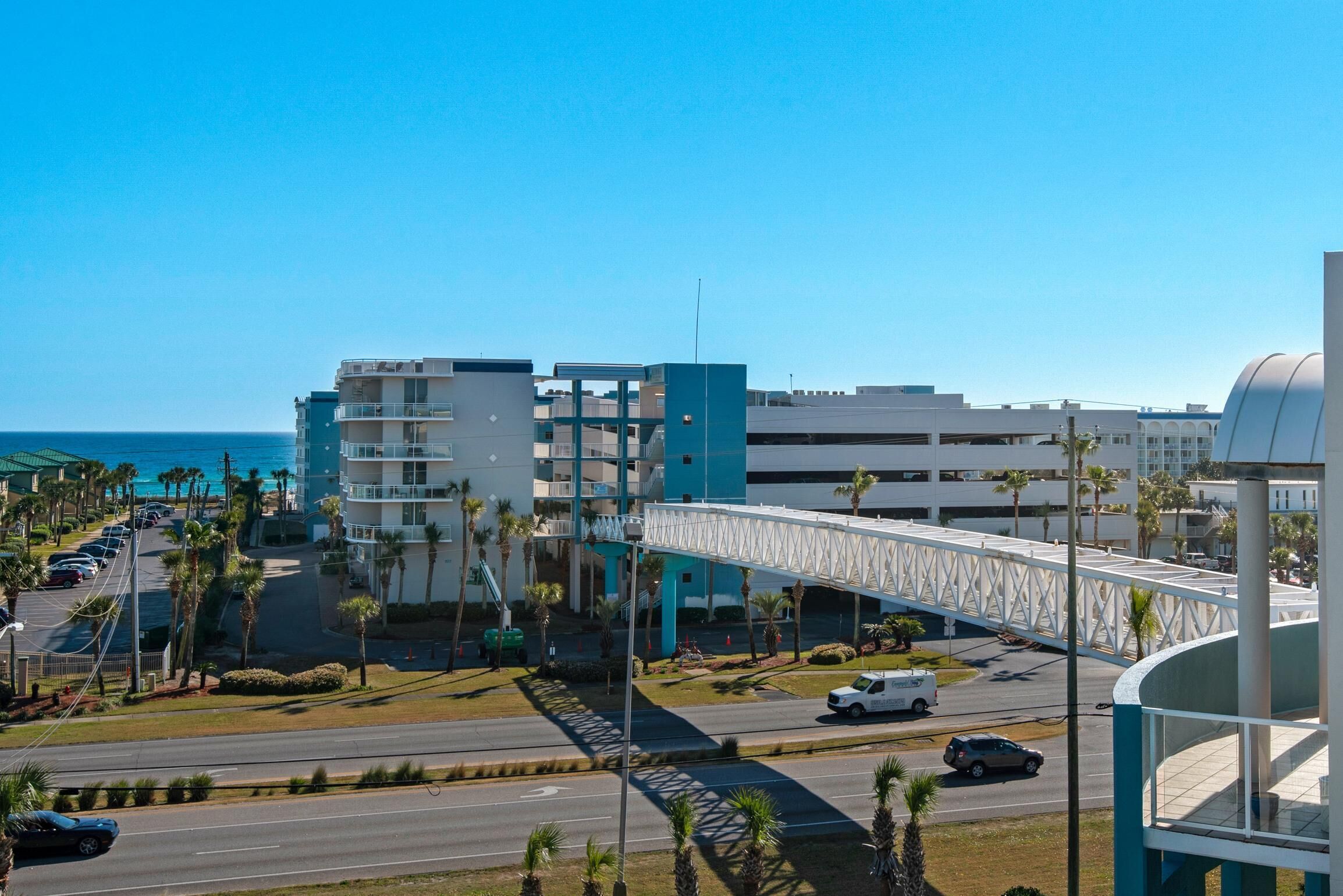 A modern building with a bridge connecting to a parking area and a road.