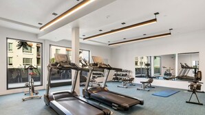 Ein modernes Fitnessstudio mit Laufbändern, Kraftgeräten und einem großen Spiegel.
