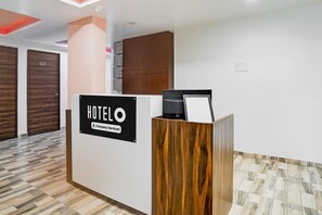 A hotel reception desk with a sign indicating it is company-serviced. - Super Hotel O Dindoli Surat (Surat)