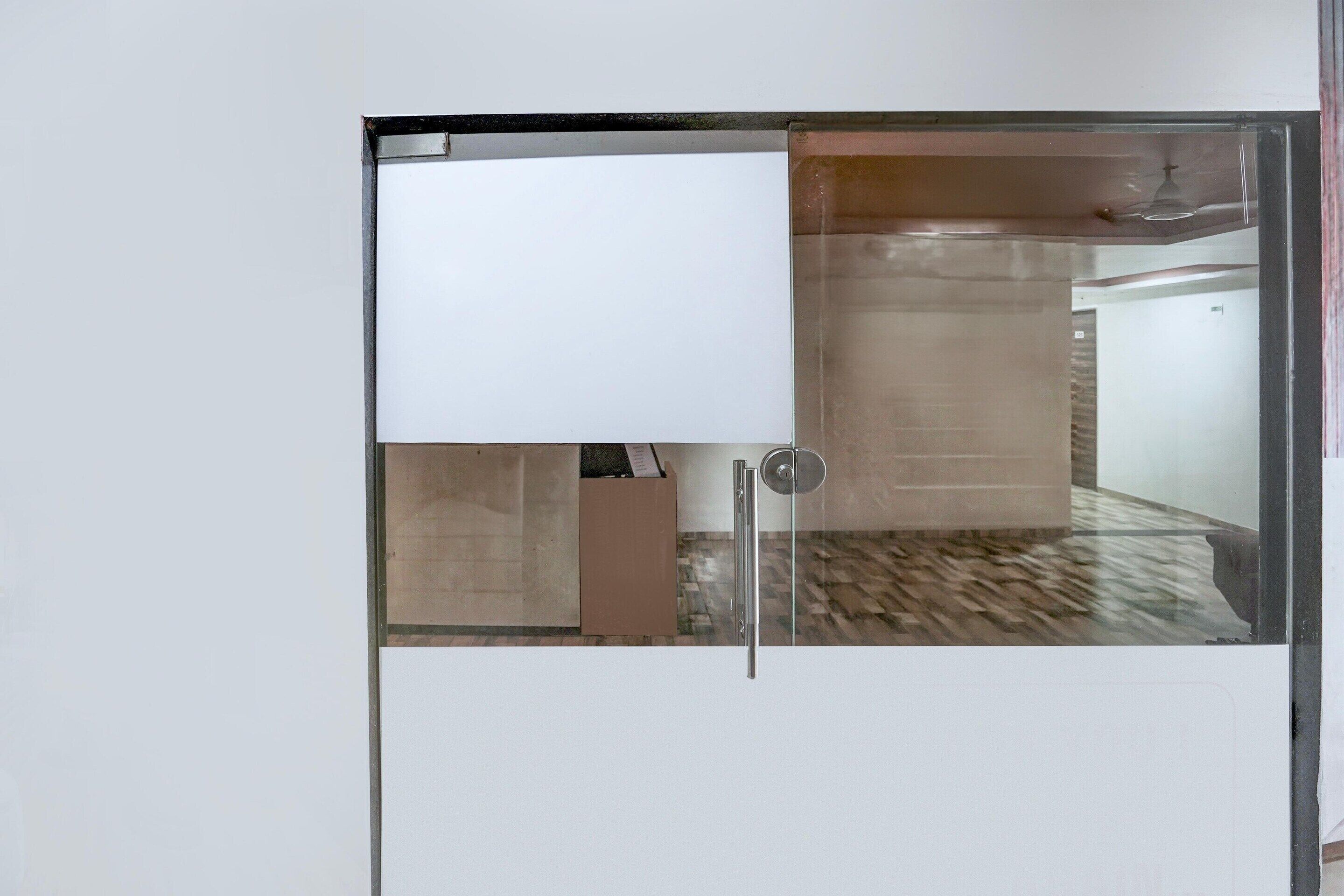 A room with a large window, a door, and a visible bathroom area.