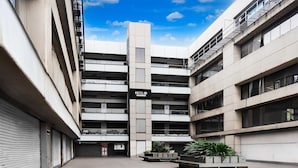 A modern hotel with a central tower, multiple balconies, and a courtyard with planters. - Super Hotel O Dindoli Surat (Surat)