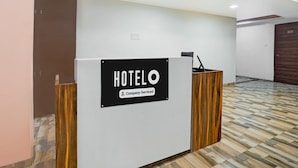 A hotel reception desk with a sign that reads "HOTELO Company Serviced." - Super Hotel O Dindoli Surat (Surat)