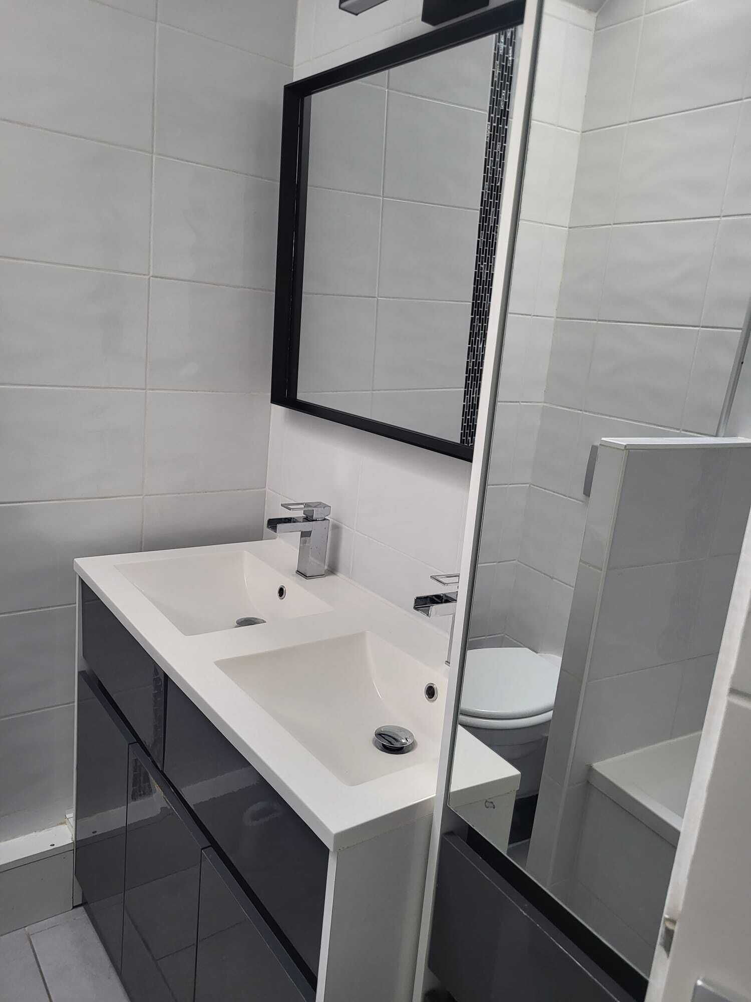 A modern bathroom with a white sink, a mirror, and a toilet.