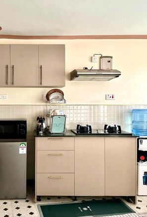 A kitchen with a microwave, stove, cabinets, and a water dispenser. - Serene 1-bedroom apartment in vibrant Nairobi perfect for your stay (Nairobi)