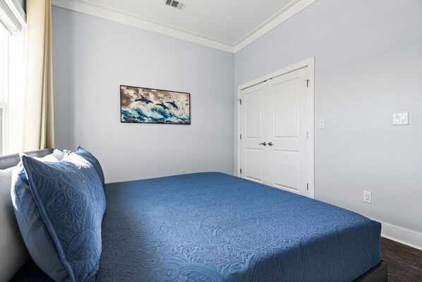 Un dormitorio con cama, puerta y un cuadro colgado en la pared.