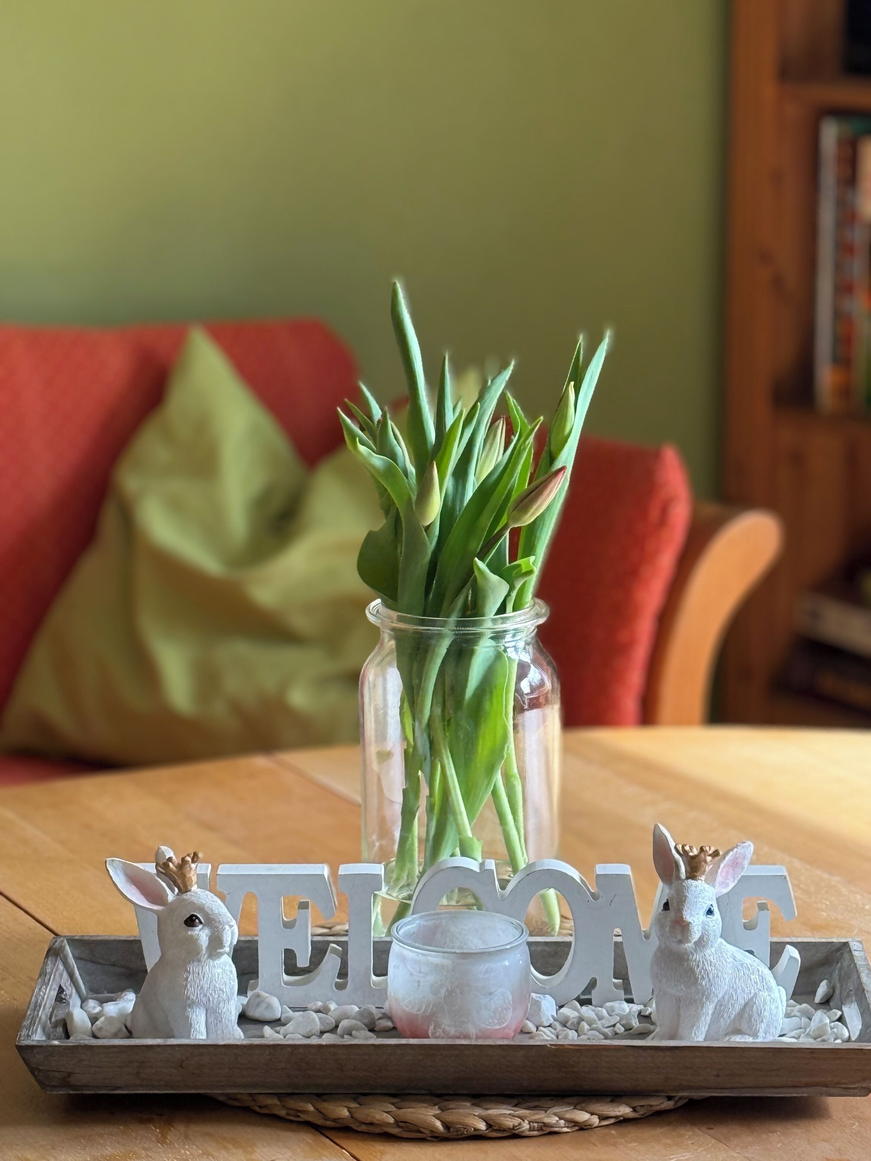 Welkom bord met een glazen pot groene planten op een houten dienblad.