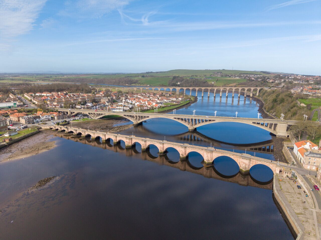 Un grand barrage avec plusieurs réservoirs d’eau, un pont et une ville en arrière-plan.