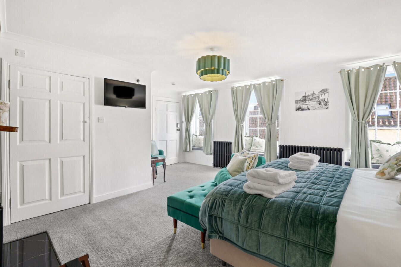 Une chambre d’hôtel avec un lit, une télévision, une fenêtre avec des rideaux, un radiateur et une chaise.