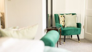 A room with a green armchair, a small side table, and a white door. - The Drawing Room at The Merchants (Berwick-Upon-Tweed)