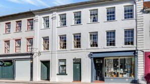 A row of white buildings with multiple windows, a green door, and a storefront with glass display windows. - The Drawing Room at The Merchants (Berwick-Upon-Tweed)