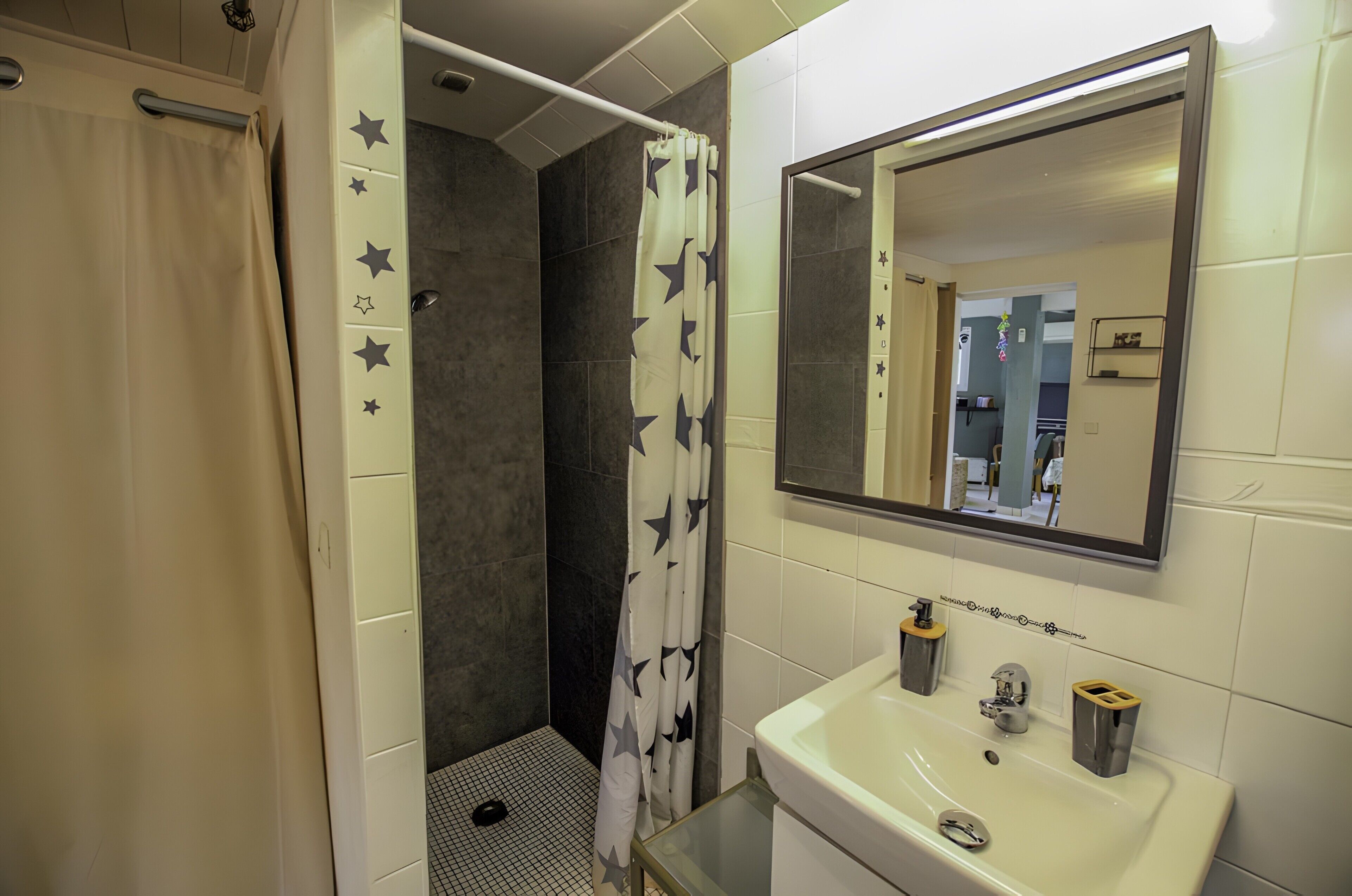 A bathroom with a shower, a sink, and a mirror.