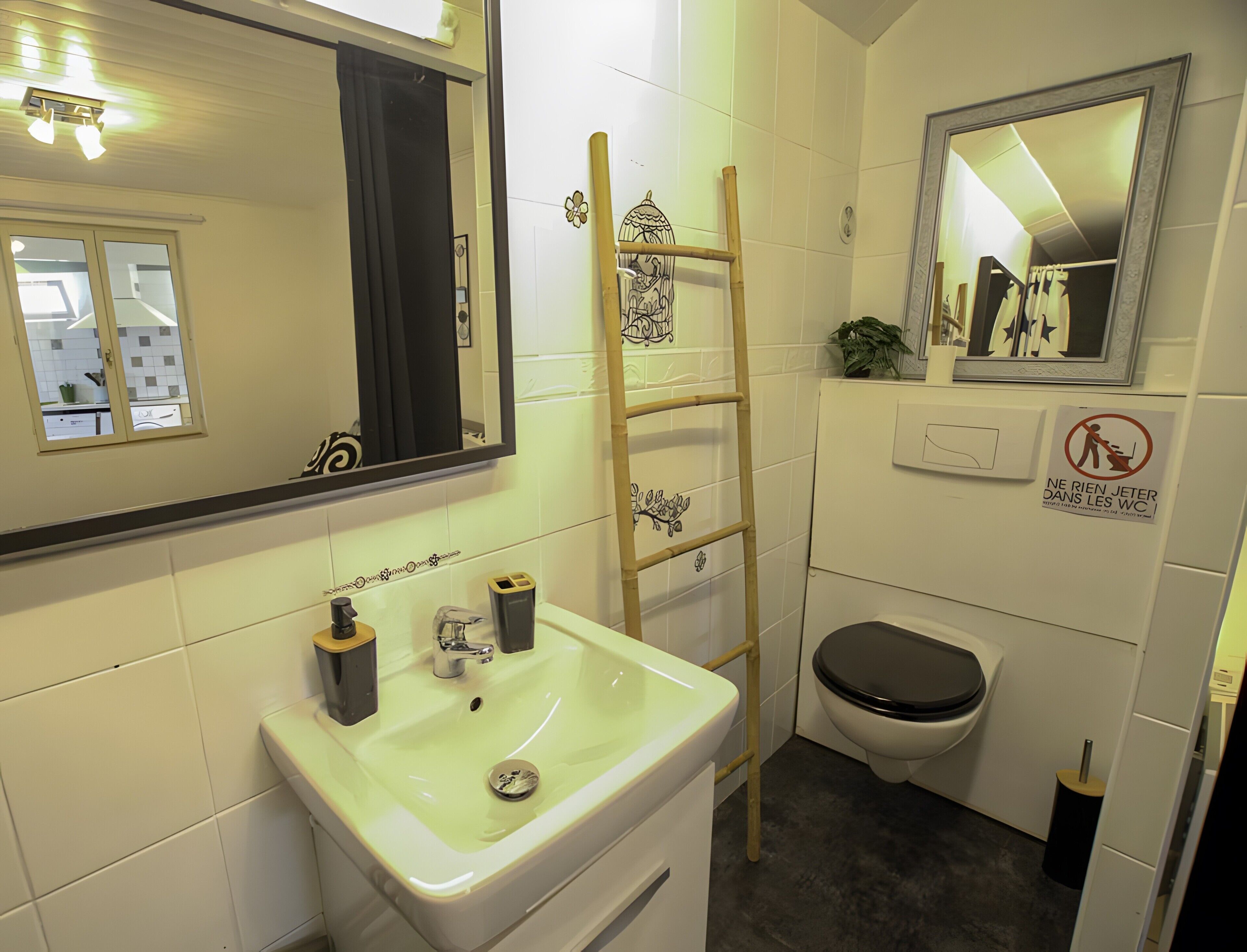 A bathroom with a sink, mirror, toilet, and a ladder.