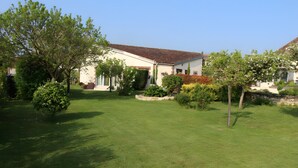 A residential property with a well-maintained lawn, a large tree, and a house with a tiled roof. - Guesthouse at the Rooster's Song (Saint-Lyé)