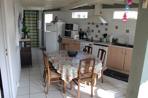 Kompakti keittiö, jossa on ruokailutila sekä mikroaaltouuni, leivänpaahdin, pesuallas ja puiset kaapit.