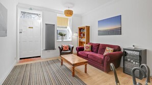 A living room with a sofa, a coffee table, a radiator, a bookshelf, and a painting on the wall. - The Morning Room at The Merchants (Berwick-Upon-Tweed)