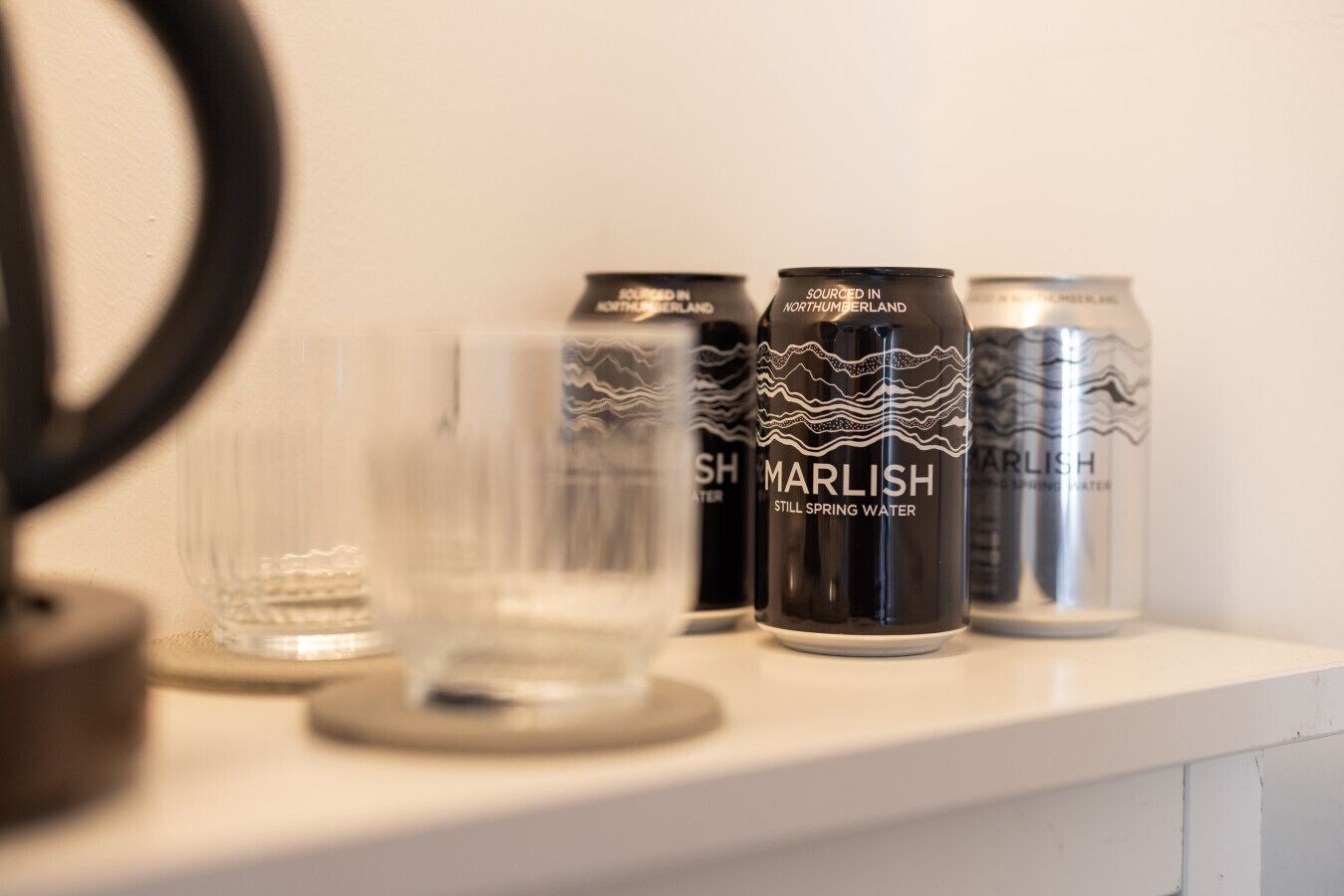 Een plank met twee glazen en twee blikjes Marlish Spring Water.