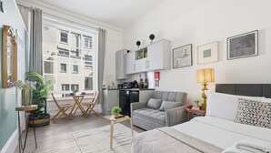 Een moderne hotelkamer met een bed, een bank, een eettafel en een kitchenette.