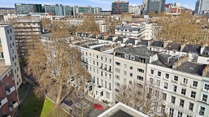 Een hoog appartementencomplex met meerdere balkons, een centrale binnentuin en uitzicht op de skyline.