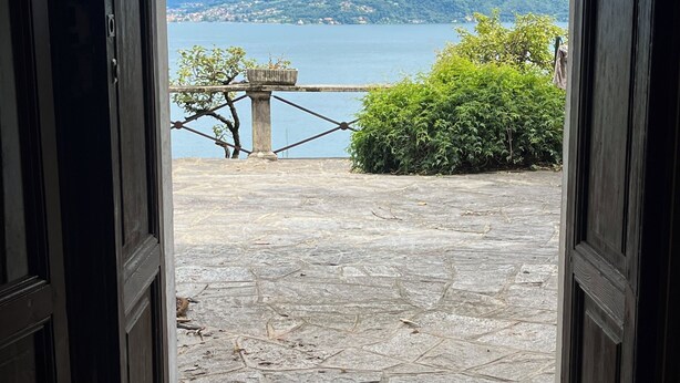 An open doorway leading to a stone patio with a view of a lake and mountains. - Stunning Lake Maggiore Villa, pool and panoramic views, timeless Italian charm (Gonte)