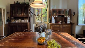 A wooden dining table with a vase of flowers and a bowl of fruit. - Stunning Lake Maggiore Villa, pool and panoramic views, timeless Italian charm (Gonte)