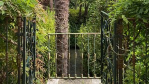A pathway leading to a gate with palm trees and a mountainous backdrop. - Stunning Lake Maggiore Villa, pool and panoramic views, timeless Italian charm (Gonte)