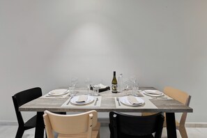 Taula de dinar preparada per a quatre persones, amb cadires, una ampolla de vi i gots.