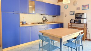 A kitchen with blue cabinets, a wooden table, and blue chairs. - S361 – Sirolo, apartment in a residence with swimming pool (Sirolo)