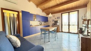 A modern kitchen with blue cabinets, a dining table with chairs, and a wooden ceiling. - S361 – Sirolo, apartment in a residence with swimming pool (Sirolo)