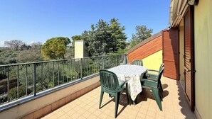 A balcony with a table and chairs, a railing, and a view of trees and buildings. - S361 – Sirolo, apartment in a residence with swimming pool (Sirolo)