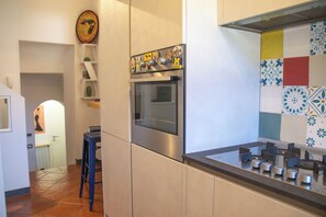A modern kitchen with a stainless steel oven, a tiled backsplash, and a blue bar stool. - Casa Zeda WelcHome (Intra)