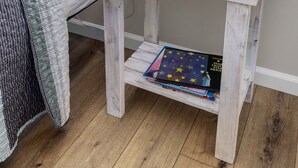 Une table de chevet en bois, avec une lampe, une petite plante en pot et un jouet en peluche.